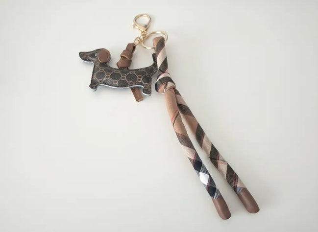dreampunk.arts dachshund bag charm with brown monogram pattern, beige plaid fabric strap, and gold lobster clasp