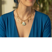 dreampunk.arts gold-tone link necklace with nautical and celestial charms and a blue floral pendant on a woman