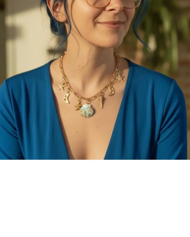 dreampunk.arts gold-tone link necklace with nautical and celestial charms and a blue floral pendant on a woman
