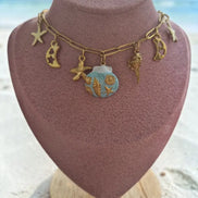 dreampunk.arts gold-tone link necklace featuring nautical starfish, moon, and blue shell charms on a display bust.