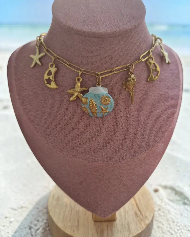 dreampunk.arts gold-tone link necklace featuring nautical starfish, moon, and blue shell charms on a display bust.
