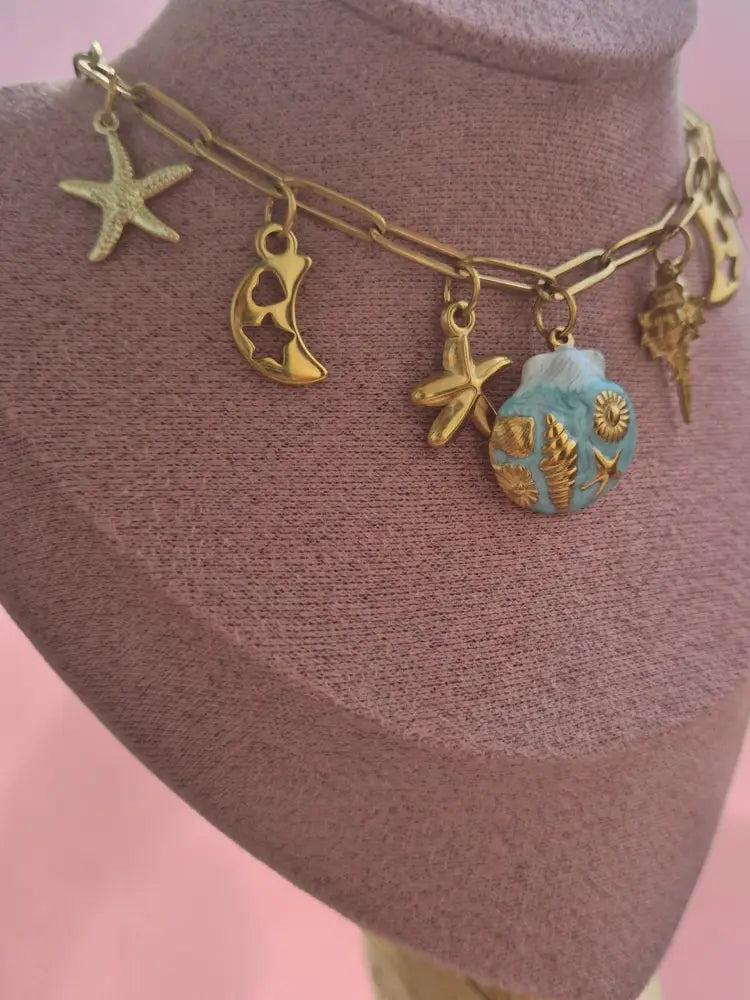 dreampunk.arts gold-tone link necklace with nautical charms, starfish, crescent moons, and a blue shell pendant.