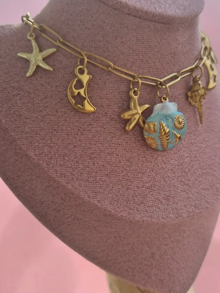 dreampunk.arts gold-tone link necklace with nautical charms, starfish, crescent moons, and a blue shell pendant.